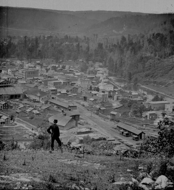 This photograph was taken overlooking the Bloss rail yard and also shows the down town section. One lone man stands at the top of the overlook.