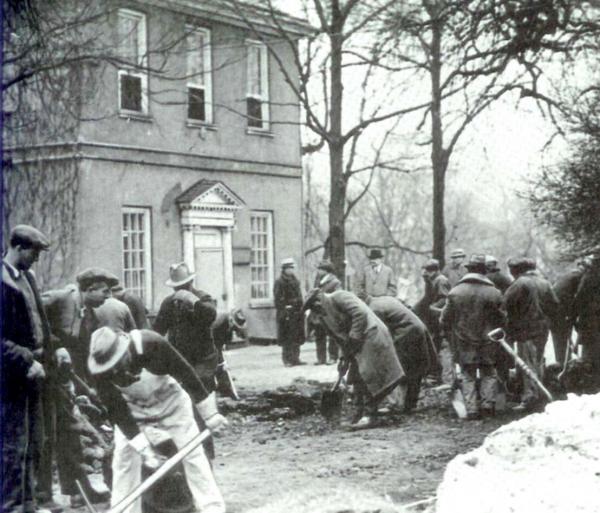 Men paving a road in front of a building.