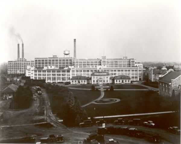 Exterior view of the Hershey Chocolate Factory and Office. View from the railroad bridge, three smokestacks, a partial view of Cocoa House, and the Hershey Cafe.
