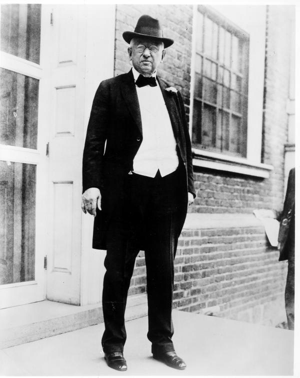 Photograph of John Wanamaker standing, wearing a tuxedo with tails, bowtie, and hat.