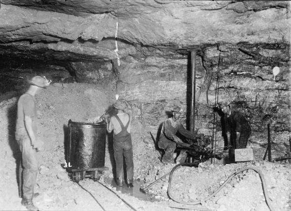Three men and one male child are at work inside of a mine.