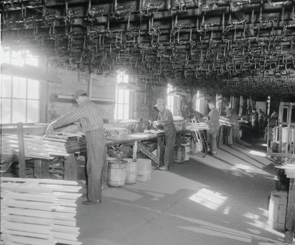 General view of the sled makers' production line.  The sled racks are overhead. The sleds are assembled in this room and passed along the line for their varnish bath.