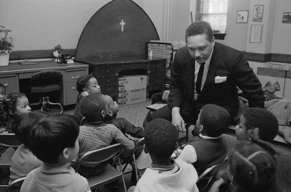 The Rev. Leon Sullivan, first Black man to become director of General Motors, talks to a group of preschool children who use his church as their kindergarten.