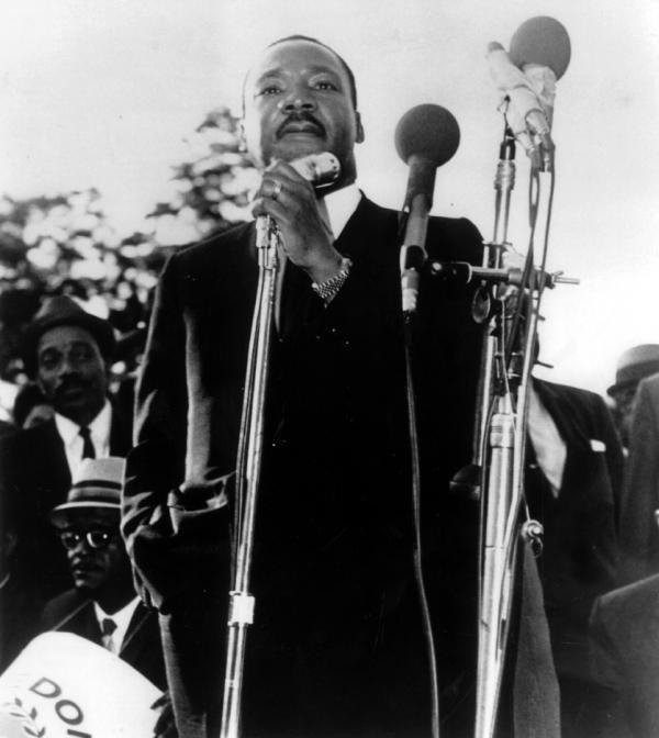 Martin Luther King, Jr. standing and speaking into a microphone.
