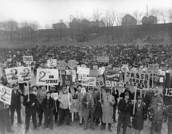 Rally to Authorize a Strike. Front View of Large Crowd at Turtle Creek Stadium on Lynn Avenue in Turtle Creek Pennsylvania. Workers Hold Signs Asking for a $2 a Day Increase. Published in the UE News December 3, 1945