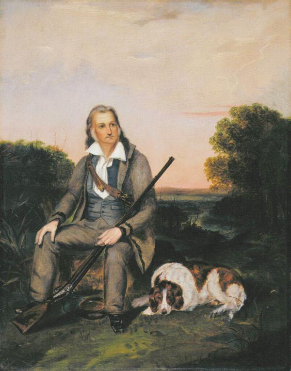 A man sitting outdoors holds a rifle. 