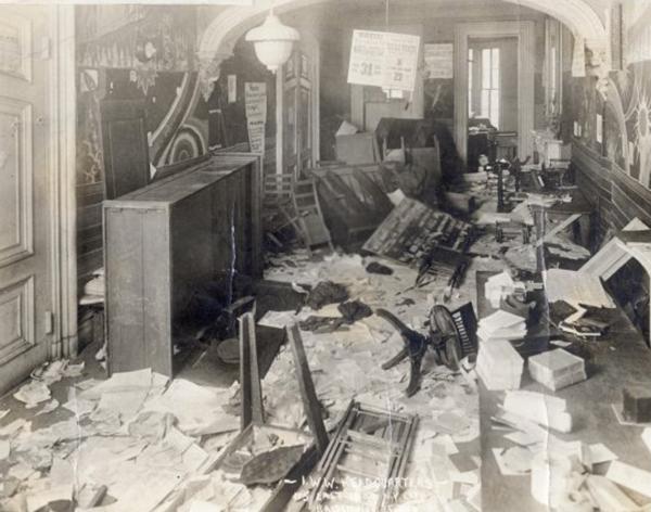 Image of an office that has been searched and items thrown on the floor and furniture overturned