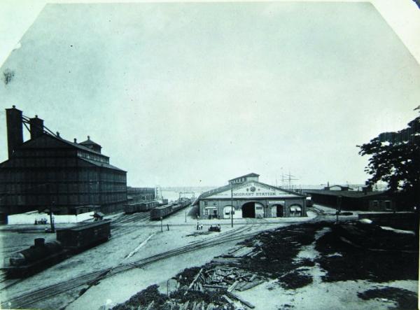 View of International Navigation Co. Emigrant Station building at Washington Avenue landing, with train tracks leading to buildings.