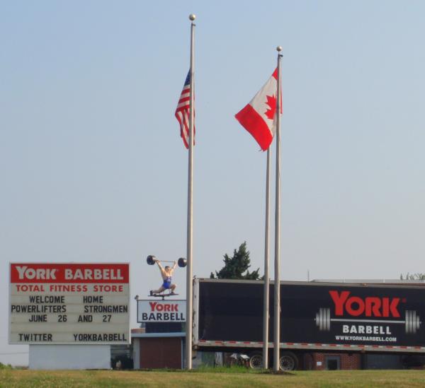 York Barbell man spins on his pedestal atop the York Barbell Total Fitness business. The marquee reads Welcome Home Powerlifters, Strongmen.