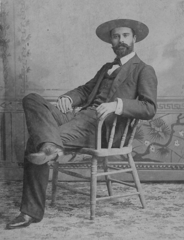Owen Wister wearing western wear and sitting in a chair.