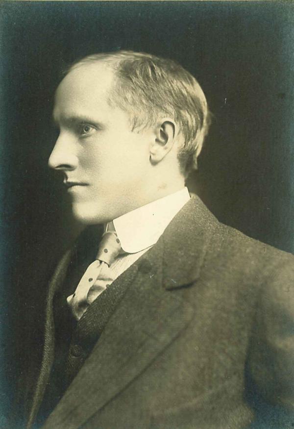 A man wearing a suit coat, vest, shirt, and tie. Side view, facing left, head and shoulders. 