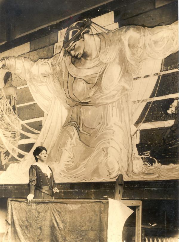 The artist stands on a scaffold in front of a portion of her 44-foot wide mural.  