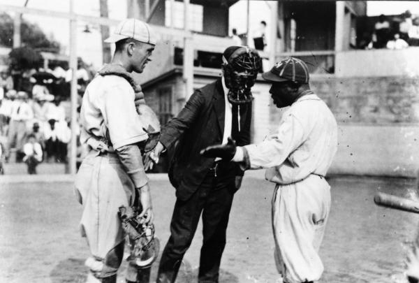 Umpire and player have a discussion while the catcher listens.