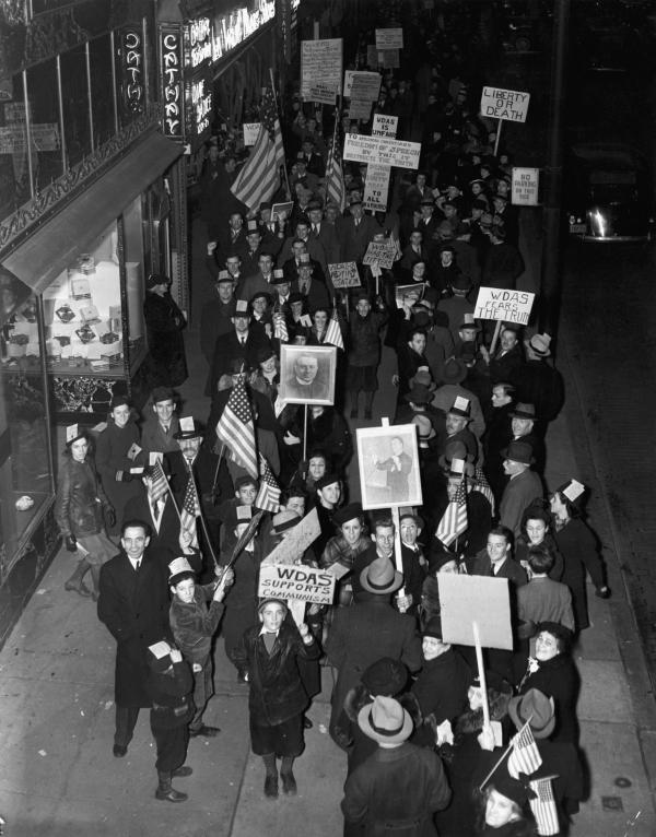 Aerial view of a group of picketers holding signs, in front of a radio station.