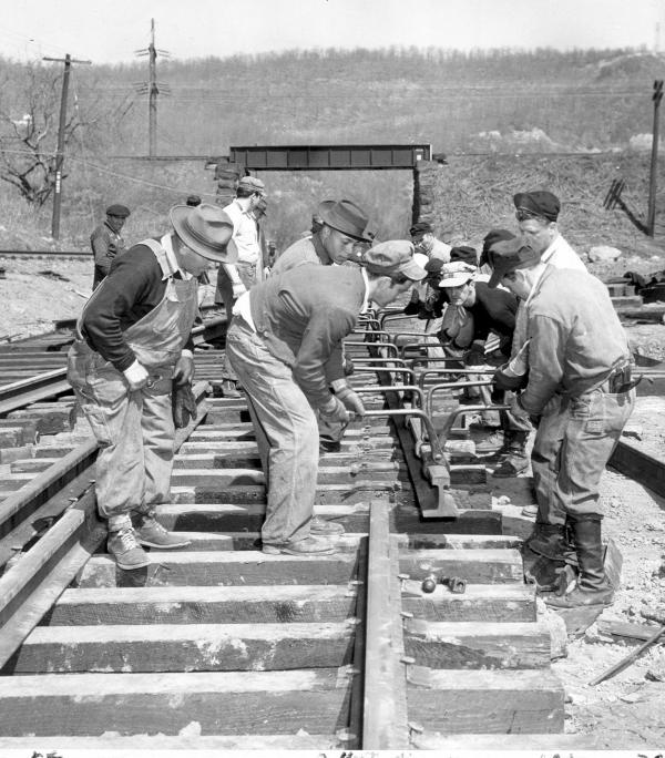 Men cutting and laying steel rails  

