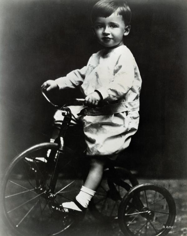 Jimmy Stewart riding a tricycle.