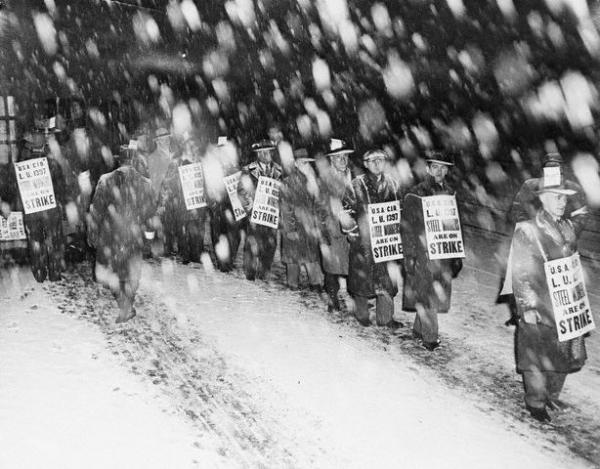 Men wearing picket signs marching in the snow.