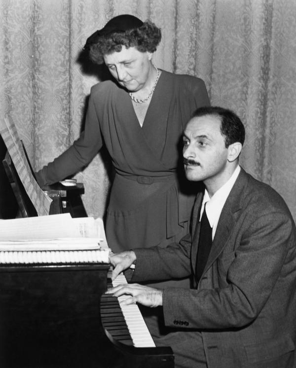 American composer Marc Blitzstein (1905-1964), shown demonstrating on the piano a passage from his "Airborne Symphony." A young woman looks on.