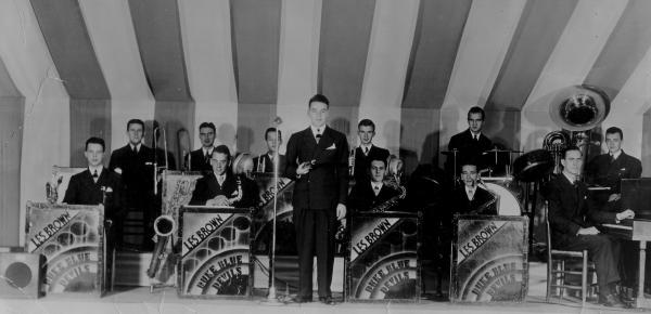 Image of the band sitting in chairs and Les Brown standing at a microphone. Front row, l to r:  Herb Muse (sax & vocalist), Joe Gardrou (alto sax), Les Brown (standing), Dutch McMillan(tenor sax), Gus Brannou (tenor sax), Coon Plyler (piano).

Back row, l to r:  Walt Moffet (trombone), Bob Thorn (trumpet), Jack Atkins (trumpet), unknown (trumpet), Don Kramer (drums), Tom Herb (tuba)

 
