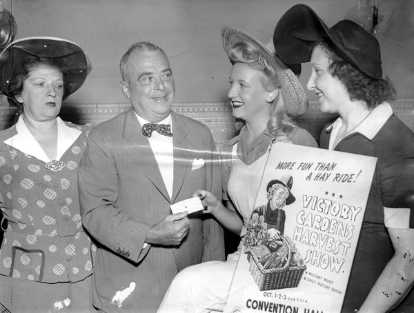 Mayor Samuels is shown buying the  first ticket for Philadelphia's Victory Garden Harvest Chow, for Army and Navy Relief. He is surrouned by three women.
