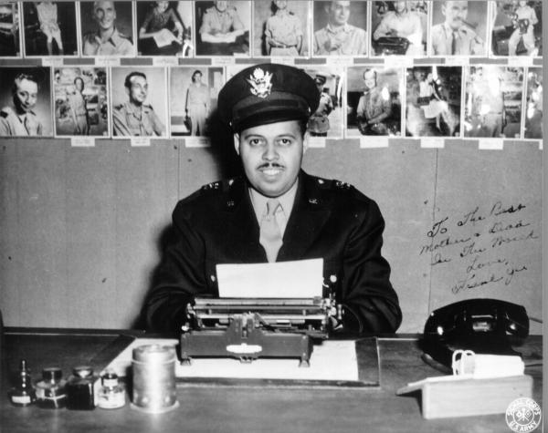 Frank Bolden in uniform at desk behind typewriter 