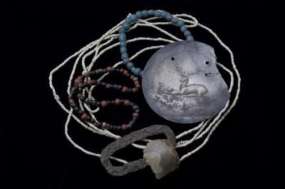 Strings of glass beads, a silver ornament with an engraved deer, and a fire starter set consisting of an English flint and iron striker, illustrate the Delaware (Lenape) Indians' dependence on trade during the 1700s.  These are among the many items collected at the Kuskuskies Town site, Lawrence County, during a 1960 archaeological investigation.