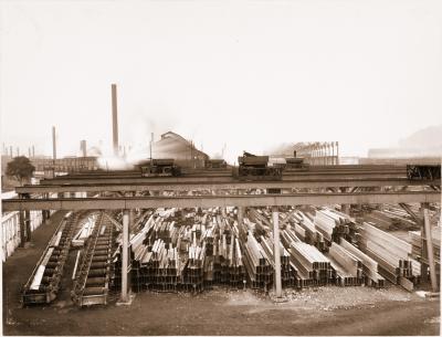 View of the 35-inch Structural Yard at the Carnegie Steel Company's Homestead Steel Works. The 35-inch Structural Mill, built in 1891, closed between 1926 and 1927. Note the two men in the center of the photograph, one lying on his side, on the large overhead cranes.