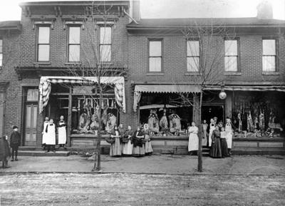 Butcher shop workers and shoppers pose outside of two Cambria City butcher shops