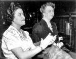 Two women seated and clapping their hands in applause.
