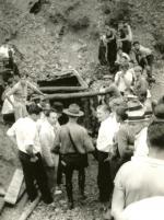 Policeman and miners stand at the entrance of a mine.