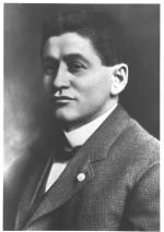Photograph of Mack, head and shoulders, wearing a suit coat and bow tie.