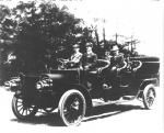 Image of a long automobile with four rows of seats. Men are seated in the rows. 