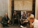 A color photograph of Jock Yablonski kneeling and talking to six sitting miners.