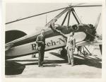 Amelia Earhart sitting in a Beech-Nut autogiro with two unidentified men standing next to the plane   