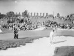 A large crowd and a caddy watch as Bobby Jones escapes a sand trap. 