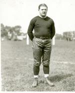 A man in uniform standing on a Ballfield.