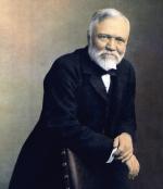 Formal portrait of Andrew Carnegie standing and leaning on the back of a leather chair. 