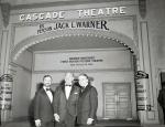 On the evening of his tribute dinner, Jack Warner (center), retiring co-founder of Warner Brothers Studios, stands with the company's chief executive officer, Ted Ashley (left), and an unidentified friend in front of the Cascade Theater in Hollywood, California.