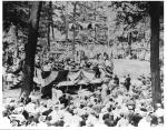 Candidate William McKinley speaks at Williams Grove on his presidential campaign trail, c.1900 from a flag draped stand while onlookers are standing below.
