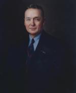 Head and shoulders portrait of Earle wearing a suit.   