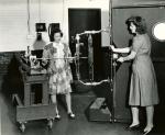 Two women pose with machinery for publicity photograph.'